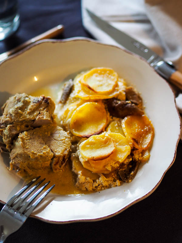 Une part de gratin au pommes de terres et au cèpes avec du filet mignon à la moutarde, recette familiale