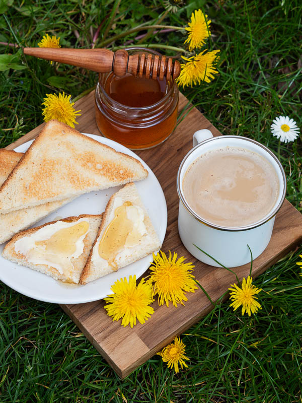 Un gouter avec du miel au pissenlit fait maison sur des tartines avec du beurre et une boisson chaude
